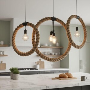 May include: Three pendant lights with large, rope-wrapped circular shades hang above a kitchen island. Each light features a black fixture and a vintage-style Edison bulb. The kitchen has white subway tile and a marble countertop.