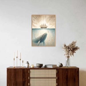 May include: A framed painting of a whale breaching the surface of the ocean, with a ship sailing above. The painting has a light blue, gray, and brown color scheme.