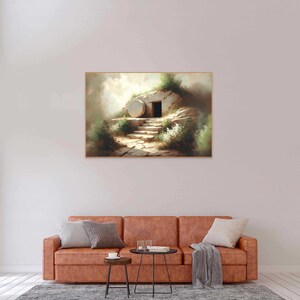 May include: A painting depicting a stone tomb with a large, round stone rolled away, revealing an open doorway. The tomb is situated on a hillside with green foliage and a path leading up to it. The scene is bathed in soft, warm light, suggesting a sense of hope and new beginnings.