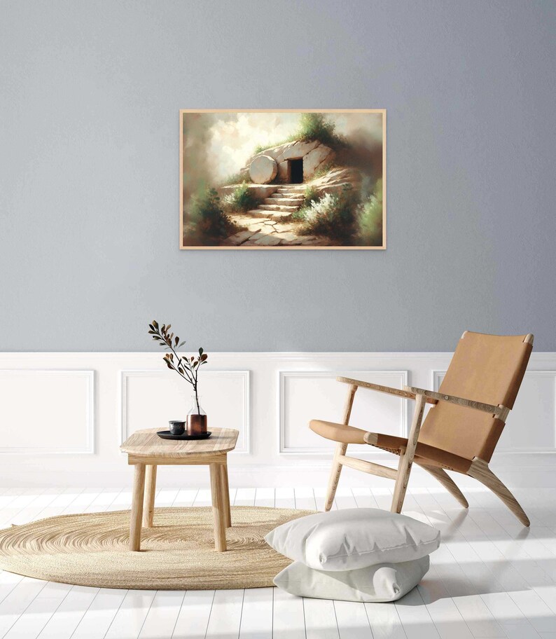 May include: A painting of a stone tomb with a large, round stone rolled away from the entrance. The tomb is set against a backdrop of a grassy hill and a cloudy sky. The painting is framed in a light wood frame.