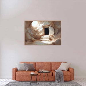 May include: A painting of a stone tomb with a large stone rolled away, revealing a doorway. The tomb is lit by a bright light coming from inside. The painting is framed and hanging on a wall above a brown leather couch.