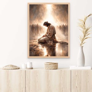 May include: A framed print depicts a religious scene with a figure kneeling in prayer, bathed in golden light. The figure wears a crown of thorns and a robe. A crowd of figures is in the background. The artwork is in a wooden frame.
