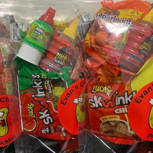 May include: Two clear plastic bags filled with various colorful candies, including red, orange, yellow, and green. The bags are labeled with the text "Lucas Skwinkis" and "Evan's C".