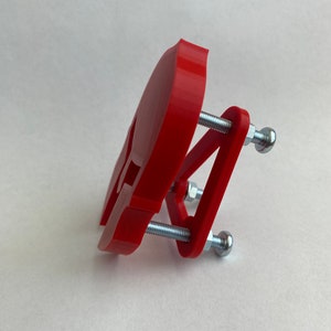 May include: A red 3D printed skull clamp with two silver screws and nuts.