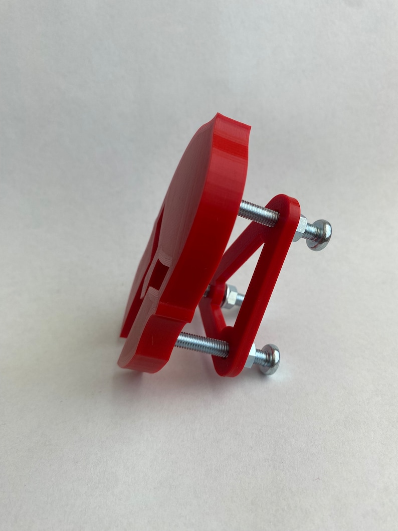 May include: A red 3D printed skull clamp with two silver screws and nuts.