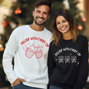May include: Two sweatshirts, one white and one black. The white sweatshirt has the text "Jollier With Every Sip" in red, with a beer mug graphic. The black one has the same text in white, with cocktail glasses.