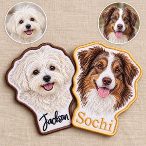 Op de afbeelding: Twee op maat gemaakte geborduurde hondenpatches. De linker patch toont een witte hond met de naam Jackson in zwart handschrift. De rechter patch toont een bruin-witte hond met de naam Sochi in gouden letters. Beide hebben randen.