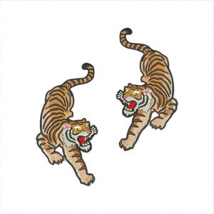 May include: Two embroidered tiger patches with orange and brown stripes, black outlines, and yellow eyes. The tigers are facing forward with their mouths open, showing sharp teeth.