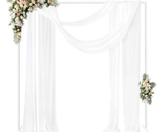 Könnte beinhalten: Eine weiße Hochzeitsbogen aus Metall, verziert mit weißen Stoffdrapierungen und Blumengestecken. Die Blumen sind eine Mischung aus rosa, pfirsichfarbenen und weißen Blüten mit grünem Laub. Der Bogen steht vor einem weißen Hintergrund.