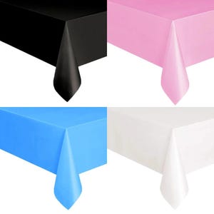 May include: Four solid-colour rectangular tablecloths in black, pink, blue, and white. Each tablecloth is folded over a corner, showing the fabric's texture and colour. Suitable for parties, events, or everyday use.