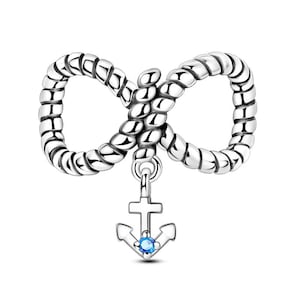 K&ouml;nnte beinhalten: Ein silberfarbener Charm-Anh&auml;nger mit einem Unendlichkeitszeichen-Design und einer seilartigen Textur. Ein kleiner Anker-Charm mit einem blauen Edelstein h&auml;ngt von der Mitte des Unendlichkeitszeichens. Der Charm ist f&uuml;r Schmuck.