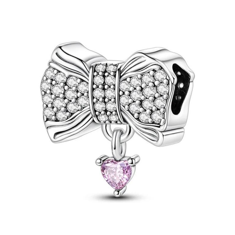 K&ouml;nnte beinhalten: Ein silberner Charm-Anh&auml;nger mit Schleifendesign, besetzt mit klaren Kristallen. Ein kleiner rosa herzf&ouml;rmiger Edelstein h&auml;ngt an der Schleife. Der Charm ist f&uuml;r ein Armband oder eine Halskette konzipiert.