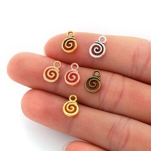 Peut inclure: Un assortiment de breloques en spirale dans différentes finitions métalliques, or, argent, or rose et bronze. Chaque breloque a une petite boucle pour l'attacher à des bijoux ou des projets d'artisanat. Les breloques sont petites et délicates.