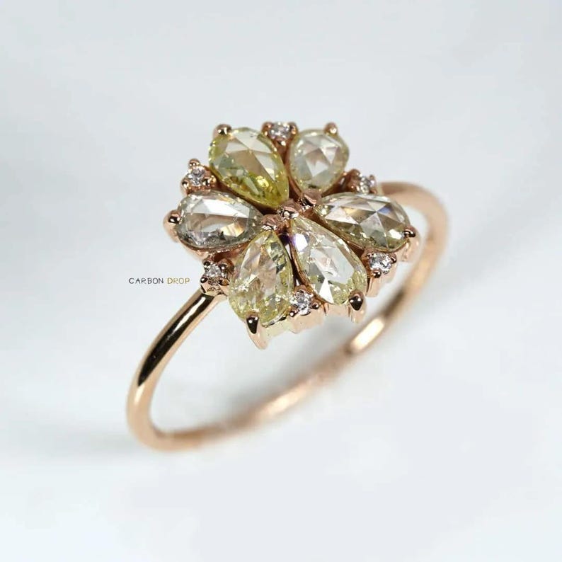 May include: A rose gold ring with a cluster of pear-shaped green and white diamonds set in a flower design.