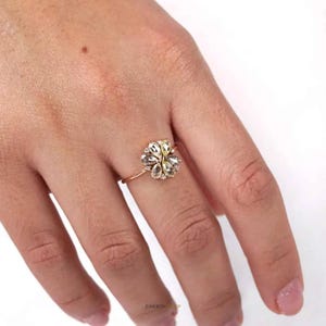 May include: A gold ring with a flower-shaped design featuring clear and yellow gemstones.
