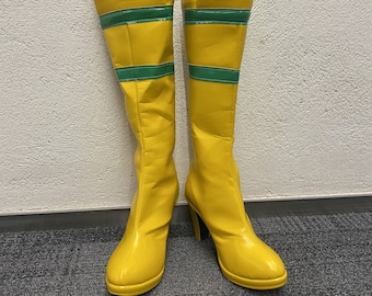 May include: A pair of yellow knee-high boots with green stripes. The boots have a high heel and a pointed toe.