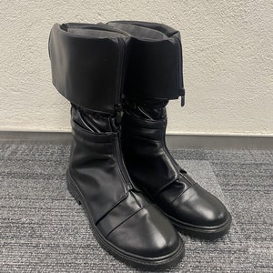 May include: A pair of black leather boots with a zipper up the side and a fold-over cuff at the top.