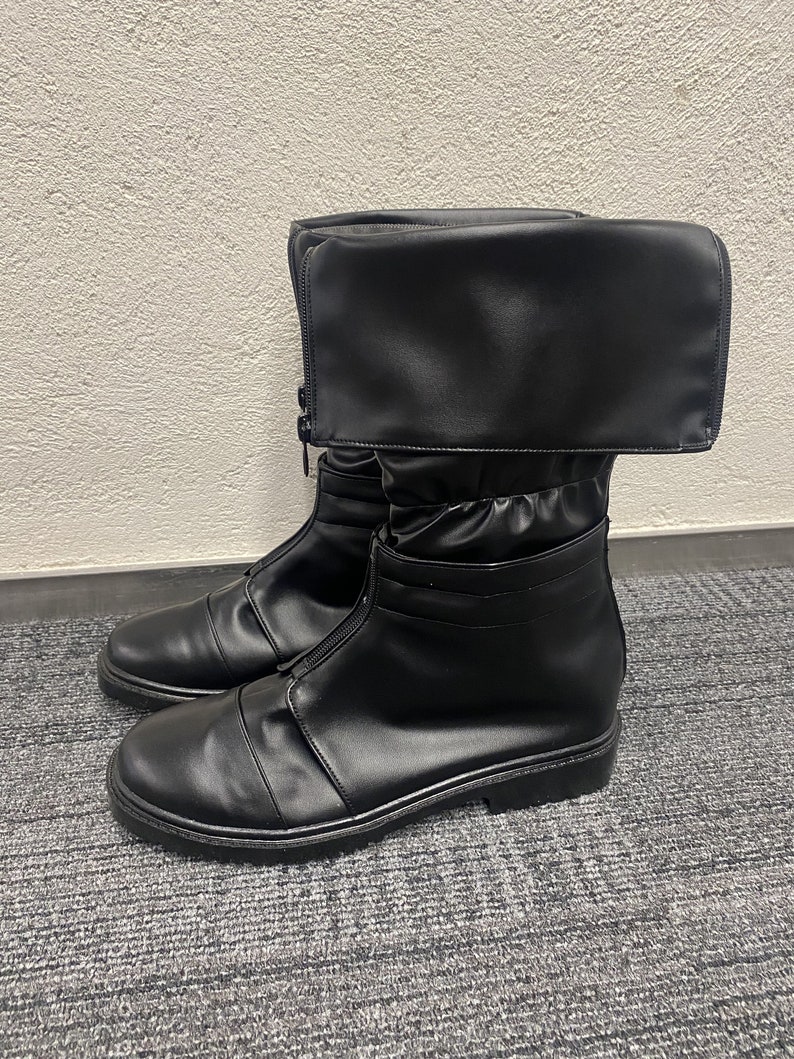 May include: Black leather boots with a fold-over cuff and a zipper up the front. The boots have a chunky sole.