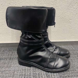 May include: Black leather boots with a fold-over top and a zipper up the front. The boots have a thick sole and a pointed toe.