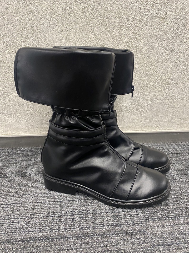 May include: Black leather boots with a fold-over top and a zipper up the front. The boots have a thick sole and a pointed toe.