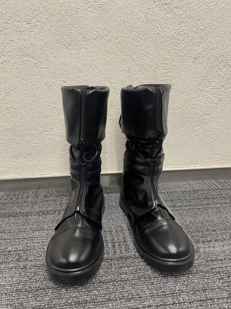 May include: A pair of black leather boots with a zipper up the front and a buckle strap around the ankle.