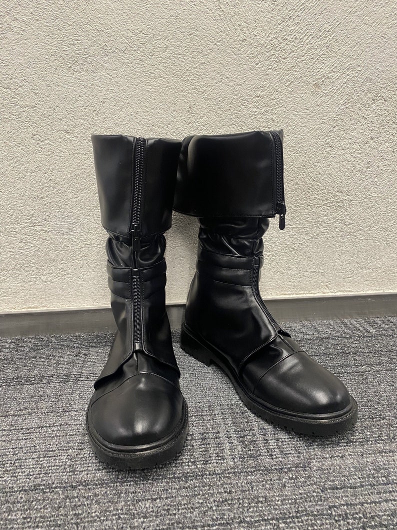 May include: A pair of black leather boots with a zipper on the side and a buckle strap. The boots have a rounded toe and a thick sole.