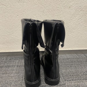 May include: A pair of black leather boots with a zipper up the back. The boots have a fold-over cuff at the top.