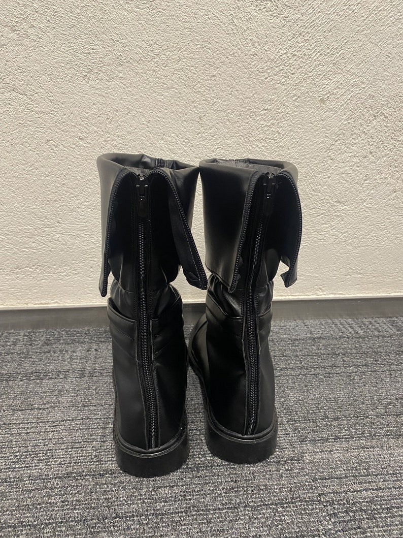 May include: A pair of black leather boots with a zipper up the back. The boots have a fold-over cuff at the top.
