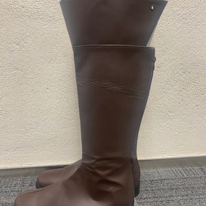 May include: A pair of brown knee-high boots with a zipper on the side. The boots have a pointed toe and a low heel.