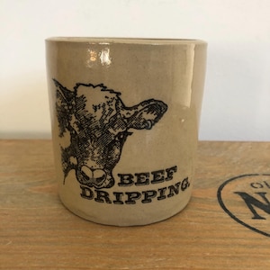 May include: A beige ceramic mug with a black and white illustration of a cow's head and the text "BEEF DRIPPING".