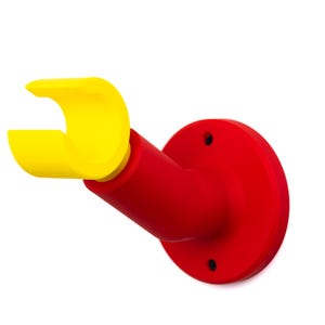 Op de afbeelding: Een aan de muur gemonteerde beugel in heldere primaire kleuren. De basis is helderrood, gaat over in een rode schuine arm en eindigt in een gele, gebogen houder. Het ontwerp is eenvoudig en modern, met een strakke, minimalistische esthetiek.