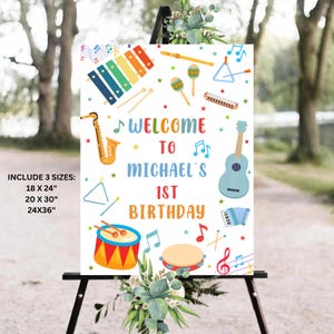 May include: A colorful welcome sign for a 1st birthday party with a musical theme. The sign features a variety of musical instruments, including a saxophone, guitar, xylophone, tambourine, and drums. The text on the sign reads "Welcome to Michael's 1st Birthday".