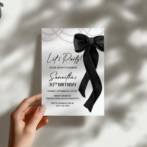 May include: A white invitation card with the text "Let's Party!" and "Samantha's 30th Birthday." A large black bow and pearl accents adorn the top right corner. The card includes RSVP information and event details.