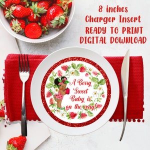 May include: A printable 8-inch charger insert with a red glitter background and a white circle featuring a cartoon illustration of a Black baby girl holding a strawberry. The text reads "A Berry Sweet Baby is on the way!"