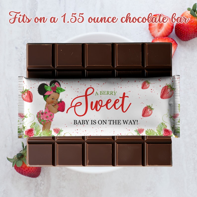 May include: A white chocolate bar wrapper with a red strawberry design and the text "A BERRY Sweet BABY IS ON THE WAY!"  The wrapper is on top of a 1.55 ounce chocolate bar.