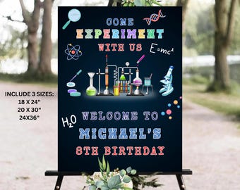 May include: A blue and black chalkboard sign with colorful science-themed graphics, including beakers, test tubes, a microscope, and a DNA strand. The text reads "Come Experiment With Us E=mc²" and "Welcome to Michael's 8th Birthday".