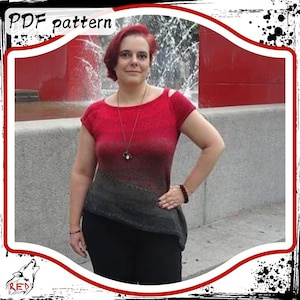 May include: A woman wearing a red and black ombre knit top with a short sleeve design. The top has a scoop neck and a slightly asymmetrical hem. The woman is standing in front of a fountain with a red wall in the background.