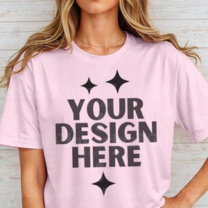 May include: A pink t-shirt with a black graphic that says "YOUR DESIGN HERE" with two stars above the text and one star below the text.