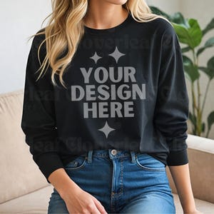 May include: Black long-sleeve shirt with the text "YOUR DESIGN HERE" in gray. The shirt is paired with blue jeans. The image is a mockup, perfect for showcasing custom designs on apparel.