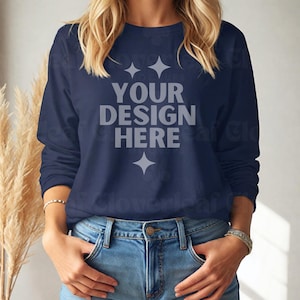 May include: A navy blue long-sleeved shirt with the text "YOUR DESIGN HERE" in white lettering.