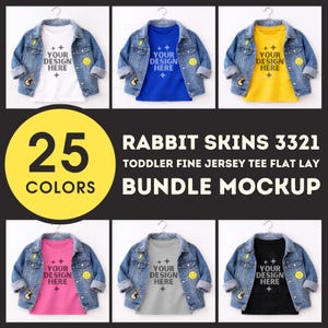 May include: A mockup of six toddler fine jersey t-shirts in various colors, each paired with a denim jacket. The t-shirts display the text "YOUR DESIGN HERE". The image also includes the text "25 COLORS" and "RABBIT SKINS 3321 TODDLER FINE JERSEY TEE FLAT LAY BUNDLE MOCKUP."