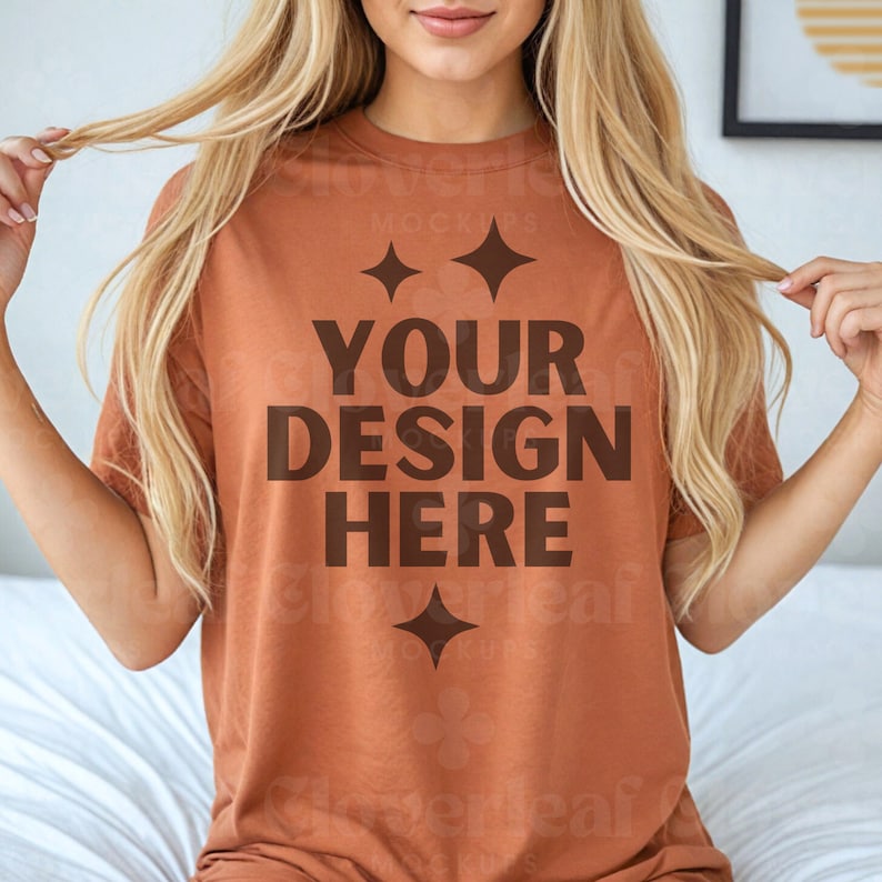 Pu&ograve; includere: Una t-shirt color ruggine con il testo "YOUR DESIGN HERE" stampato in marrone. La t-shirt ha una vestibilit&agrave; rilassata ed &egrave; realizzata in un tessuto morbido e confortevole.
