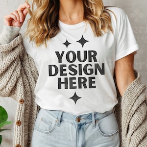 以下が含まれることがあります： 白いTシャツに黒い文字で「YOUR DESIGN HERE」と書いてあり、小さな星が4つ付いています。