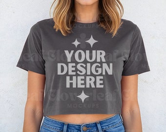 May include: A charcoal gray cropped t-shirt with short sleeves and the text "YOUR DESIGN HERE" printed in white. The shirt is being modeled by a person with long brown hair.