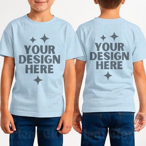 May include: Light blue t-shirts with the text "YOUR DESIGN HERE" in gray, displayed on a child. The front and back of the shirt are visible. The shirts have a crew neck and short sleeves. The text is above a diamond-shaped design.