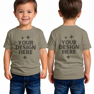 May include: A child's olive-green t-shirt with the text "YOUR DESIGN HERE" in dark grey. The t-shirt has short sleeves and is worn with blue jeans. The image shows the front and back of the t-shirt.