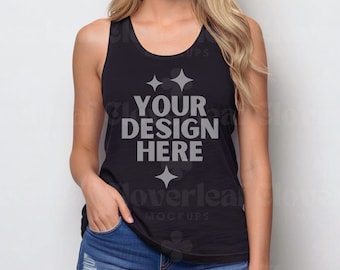 Puede incluir: Un top negro de tirantes con el texto "YOUR DESIGN HERE" en gris. El top está siendo modelado por una persona que lleva pantalones cortos de mezclilla.