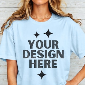 May include: A light blue t-shirt with a black graphic that says "YOUR DESIGN HERE" with two stars above the text and one star below the text.