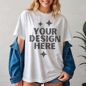 Puede incluir: Una camiseta blanca con un diseño gráfico que dice "YOUR DESIGN HERE" en texto negro con cuatro pequeños diamantes alrededor del texto.