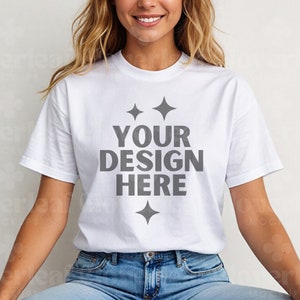 Könnte beinhalten: Weißes T-Shirt mit einem grauen Textüberlagerung, auf dem "YOUR DESIGN HERE" steht, und zwei kleinen grauen Sternen über und unter dem Text.